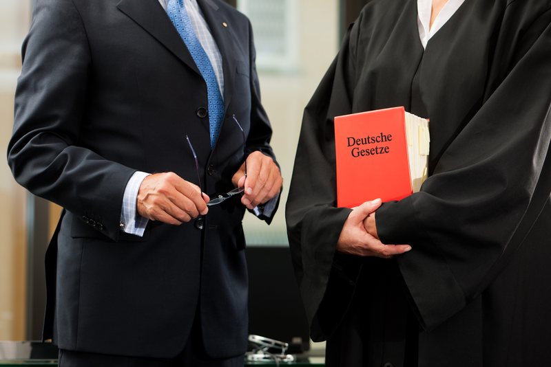 Two attorneys, one in a robe holding a German law code