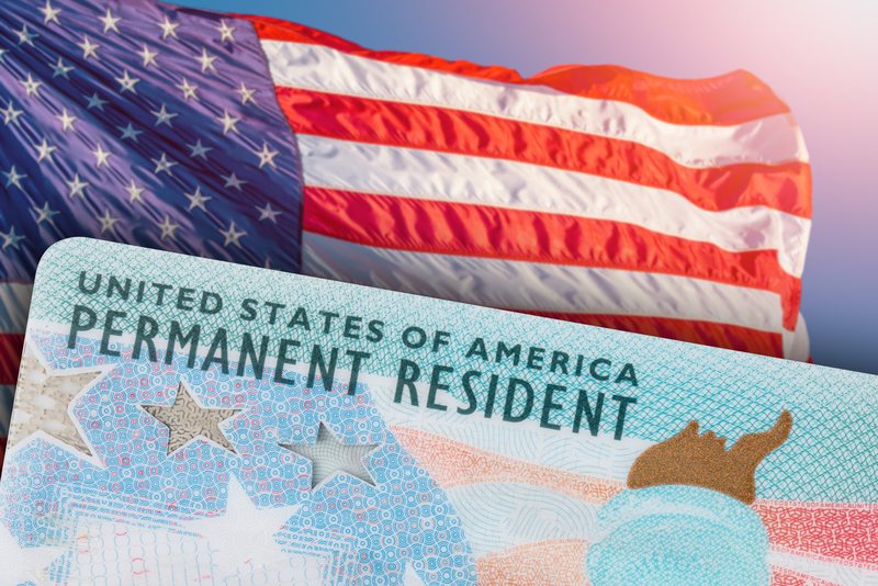 A U.S. permanent resident card in front of the American flag